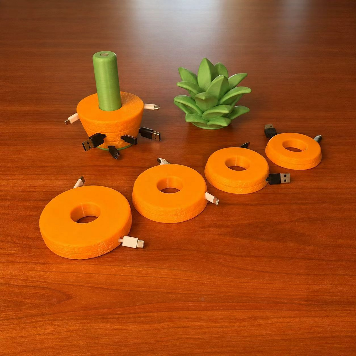 Orange cable slices in different sizes, each holding one wound cable, beside the pineapple base and leaf top