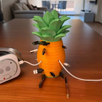 Pineapple cable organizer on a wooden dining table holding several charging cables